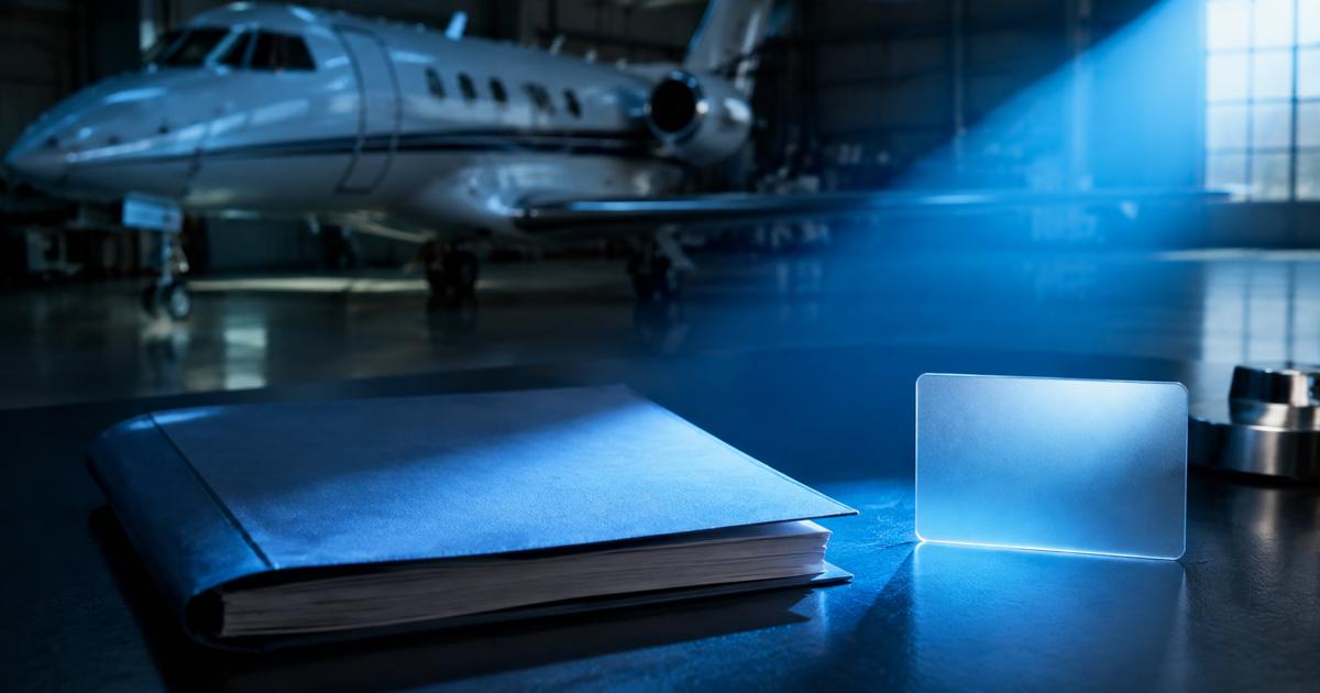 An unmarked document folder and translucent card on a blue-lit desk in an aircraft hangar